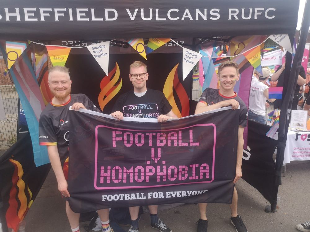 A photo of me holding the Football v Homophobia banner with two Sheffield Vulcans players at Kelham Pride.