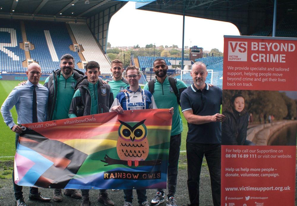 A photo of me holding the Rainbow Owls banner with Michael Ihiekwe, Callum Paterson, Will Vaulks and John Buckley at Hillsborough Stadium for Hate Crime Awareness Week.