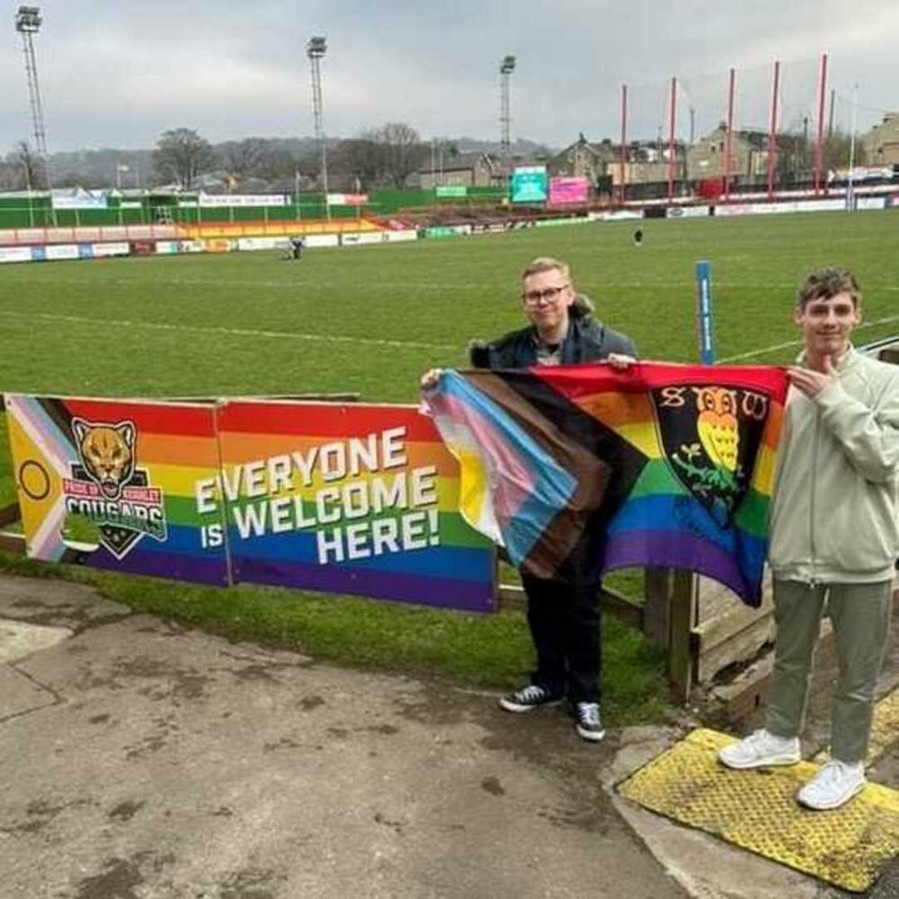 Me holding SWFC's Progress Pride flag with fellow Rainbow Owls member Tyler James at Cougar Park.