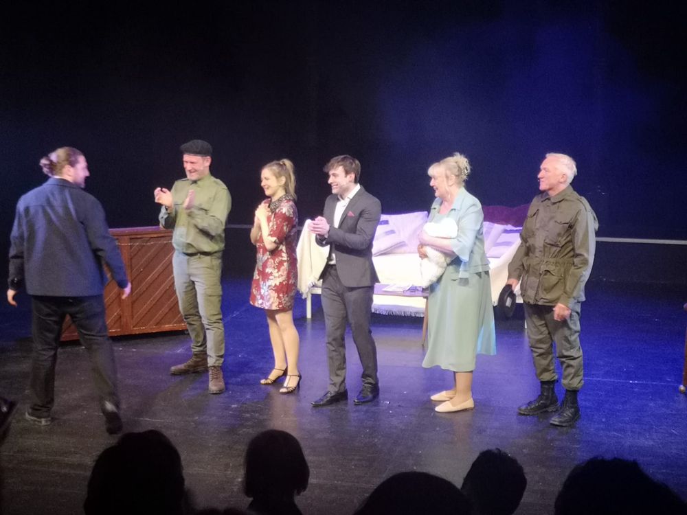 A photo of How Could I Forget? cast members applauding Joe Carnall Jnr from stage at the University of Sheffield's Drama Studio.