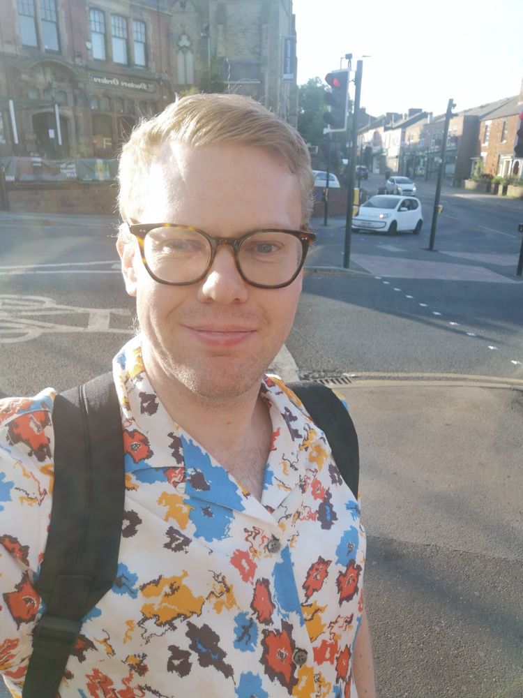 A selfie of me in Sheffield City Centre while wearing a floral shirt with a rucksack on my back.