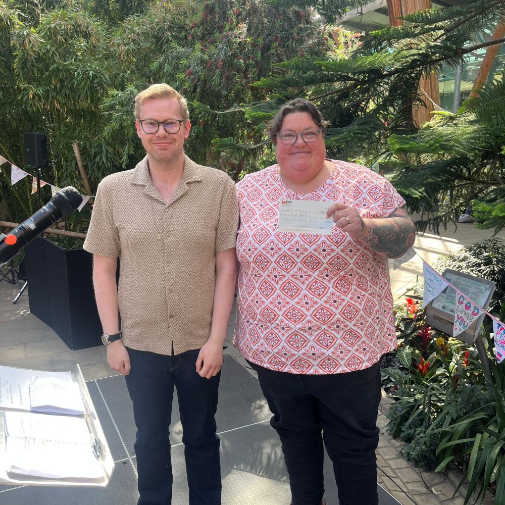 A photo of me presenting a cheque to SAYiT's CEO, Nicola Fearnley-Hill, at their IDAHOBIT event in the Sheffield Winter Garden.