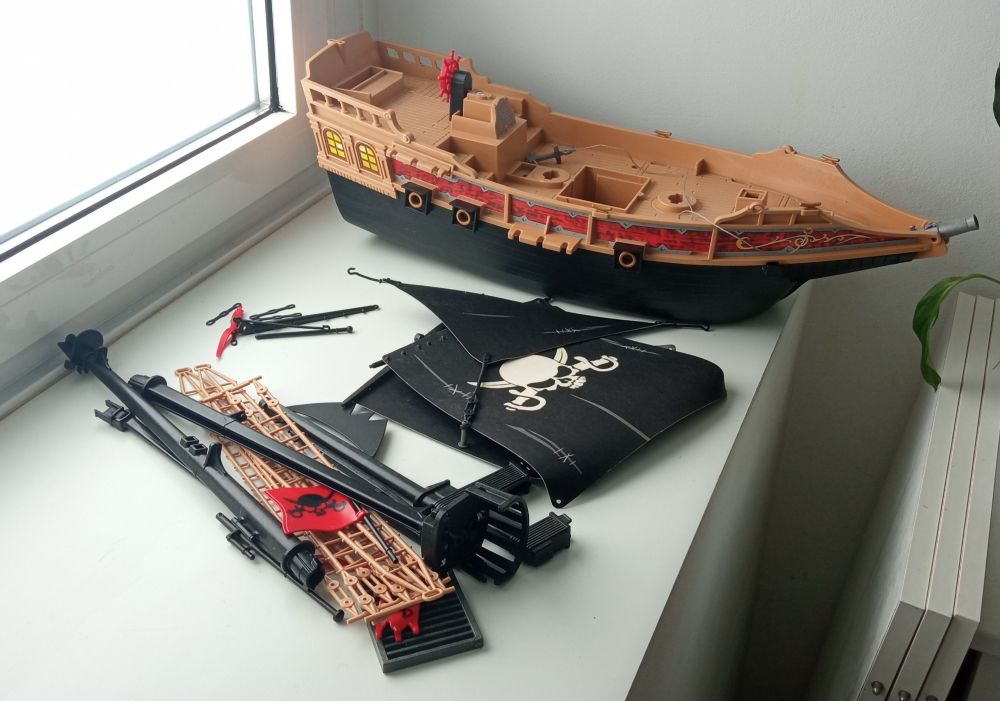 Goleta pirata de playmobil medio desmontada para poder limpiarle el polvo. Separada por arboladura, velamen y casco