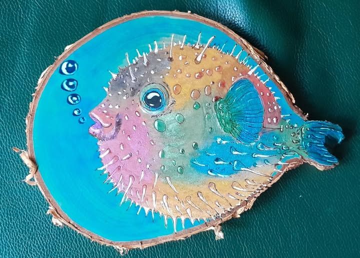 A pyrography (wood burning) piece of a pufferfish blowing bubbles. The outline is burned onto wood and then he has painted colour onto it.

This piece of wood had a weird shape, and the idea came to him as a result (there is a weird bit on the end that looks like a fish's tail).