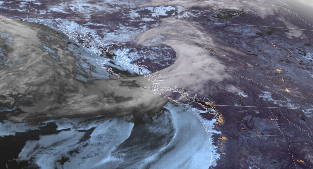 A satellite image of British Columbia showing a comma shaped cloud pattern over the province indicating a low pressure system and cold front.