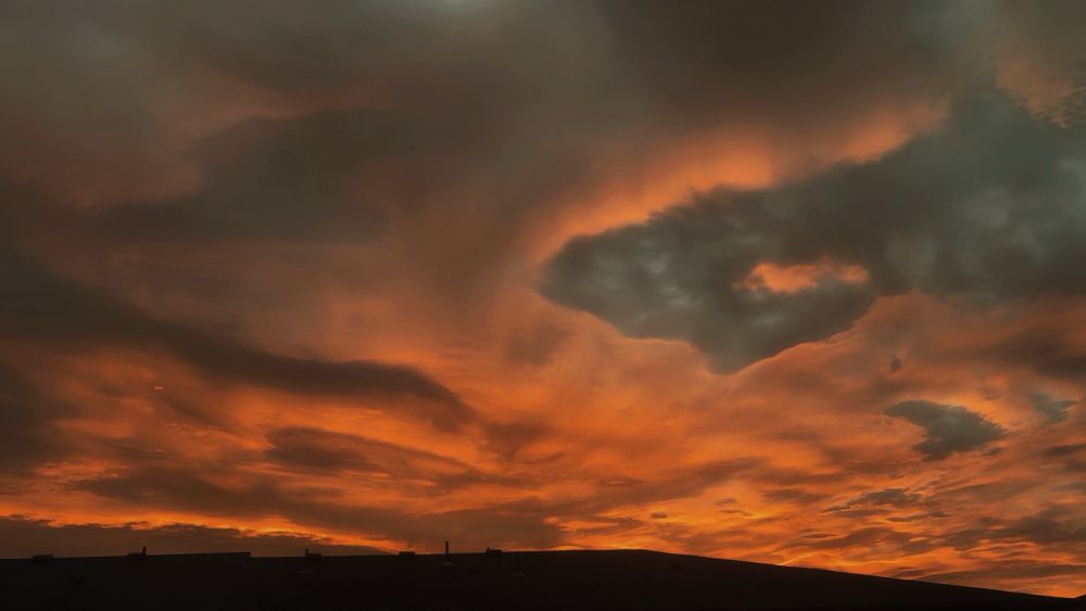 The sunrise this morning with clouds in the sky, the sunrise making the clouds look orange 
