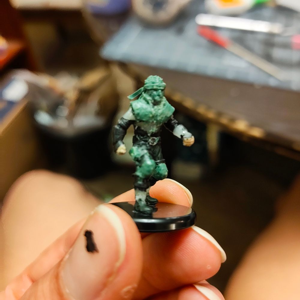 The previous miniature has had some details removed and others added via "green stuff" epoxy. It's starting to resemble Solid Snake in his sneaking suit from MGS1.