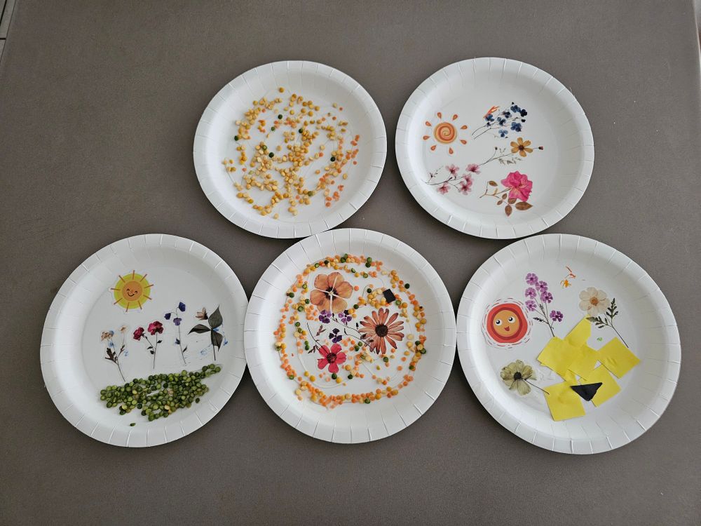 Five paper plates with a range of crafted images on them.
