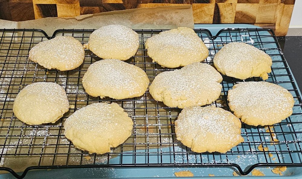 Ten sugar cookies of various size on a wire cooling rack.