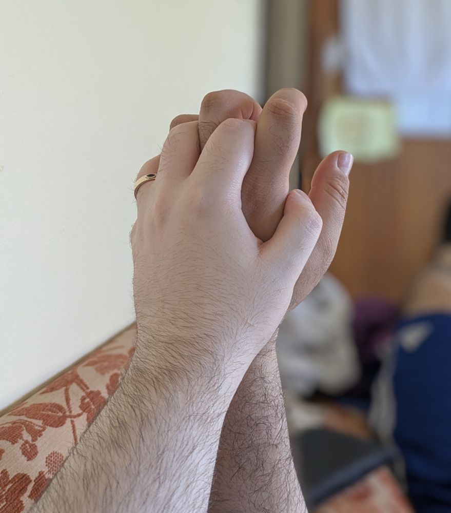 David's hand with fingers intertwined with his fiancée's.