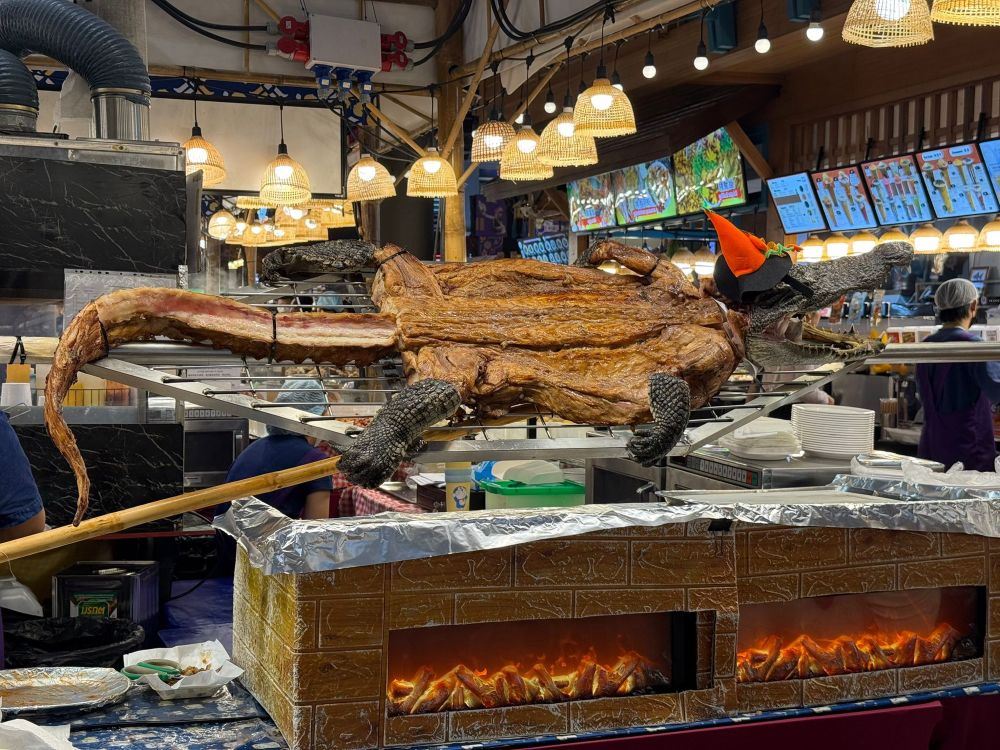 cooked whole gator on display at a restaurant wearing a little halloween witch hat 