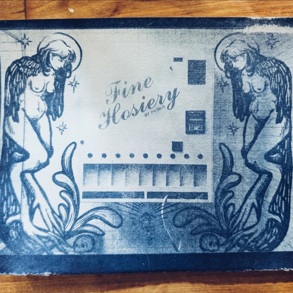 Two harpy like women flanking an old out of use hosiery dispenser, done with cyanotype 