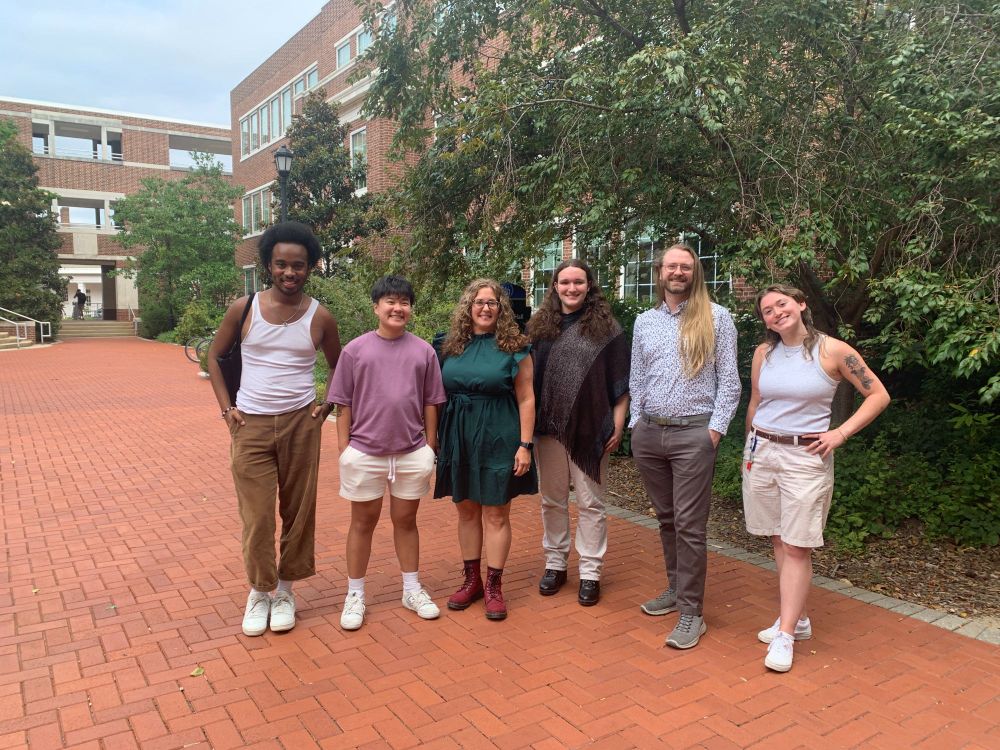 Photo of Queer Development lab members standing outside a building on campus. Picture shows six pople standing together.