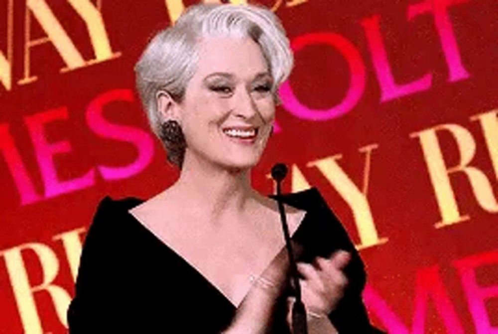 a woman in a black dress is standing in front of a microphone and smiling .