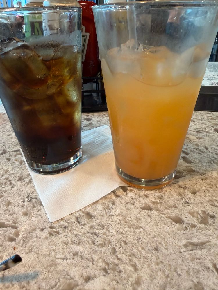 Picture of two drinks close up. The one on the left is a coke and the one of the right is a spiced rum punch.