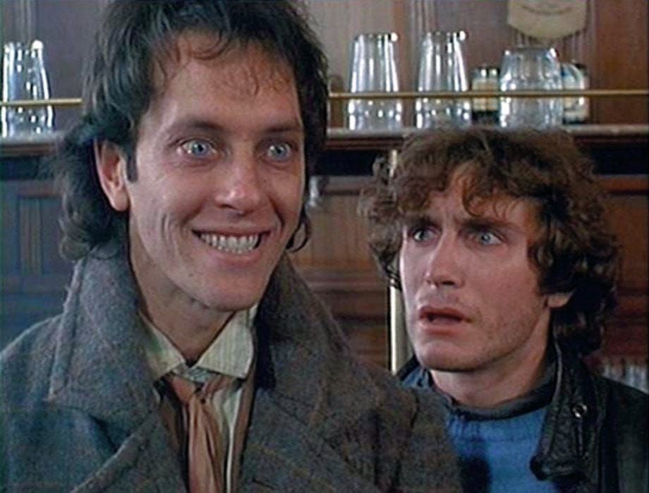 Richard E Grant playing Withnail perfects a glassy eyed a manic grin while Paul McGann as Marwood looks on in bewildered horror