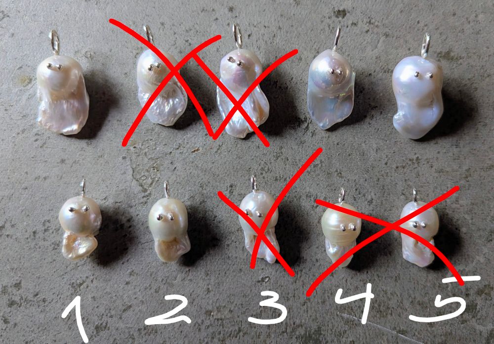 10 Perlen mit Augen, die wie Geister aussehen auf einem grauen Tisch