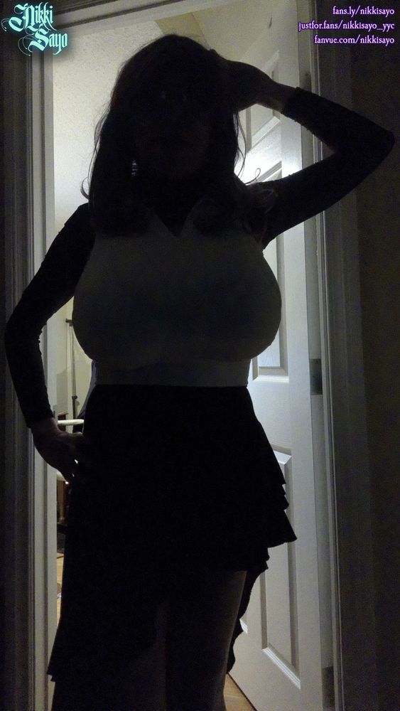 A feminine silhouette sporting long hair, huge tits covered by a white crop top, and a black asymmetric skirt