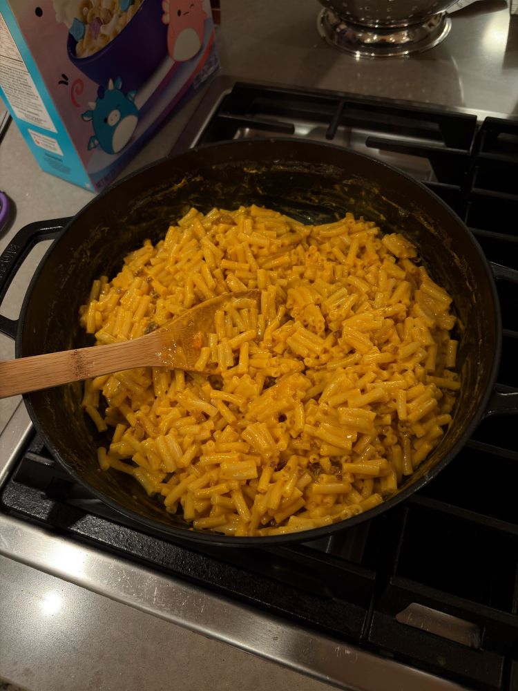 A dark cast iron braiser filled with box Mac and Cheese.