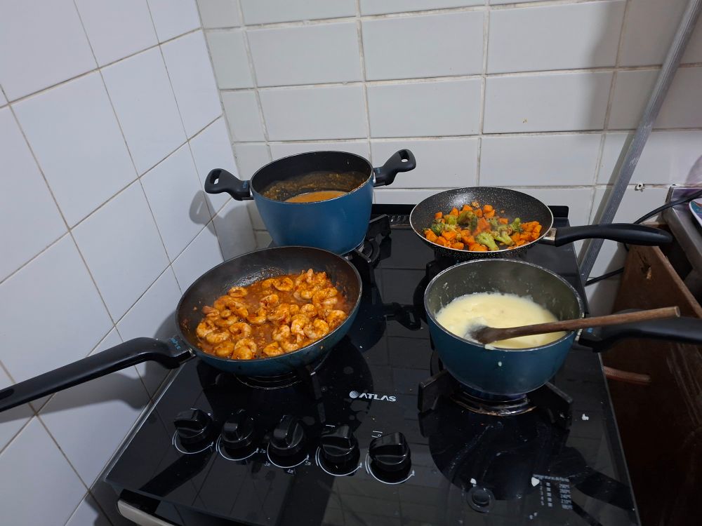 4 panelas num fogão 
Um de grao de bico, legumes manteiga, camarão grelhado com páprica, pimentão e alho na ultima, um purê de batata