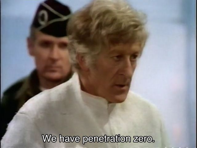 Jon Pertwee episode. The Doctor is wearing a bright white uniform of some kind, in a bright modern room. A soldier is standing right behind him, a bit out of focus. The Doctor is looking off-screen, in slight shock, mouth a little bit agape. Caption reads, “We have penetration zero.”