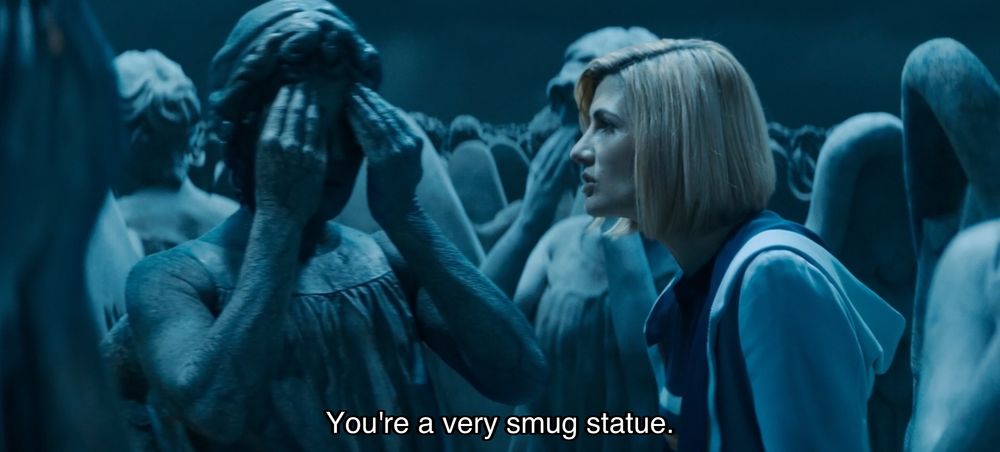 Jodie Whittaker episode. The Doctor is standing among a field of Weeping Angels, statues with wings covering their eyes. Caption reads, “You’re a very smug statue.”