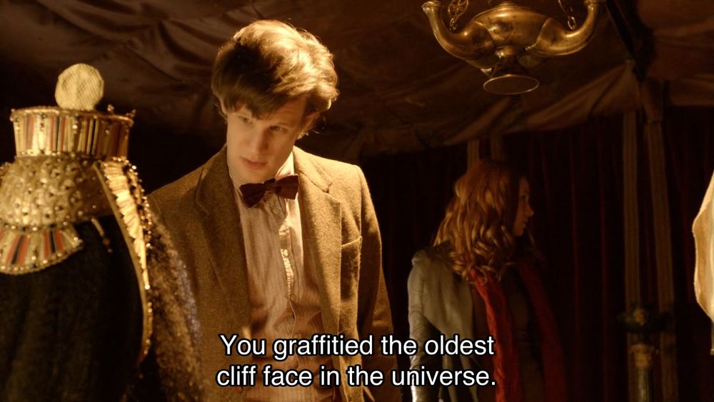 Matt Smith episode. The Doctor, Amy Pond and River Song are in a Roman army tent. It’s generally a bit dark, but somehow the few candlelights are fully illuminating the three just like TV studio lighting would. How odd. The Doctor says, “You graffitied the oldest clift face in the universe.” River, inexplicably dressed as Cleopatra, says, “You wouldn't answer your phone.”