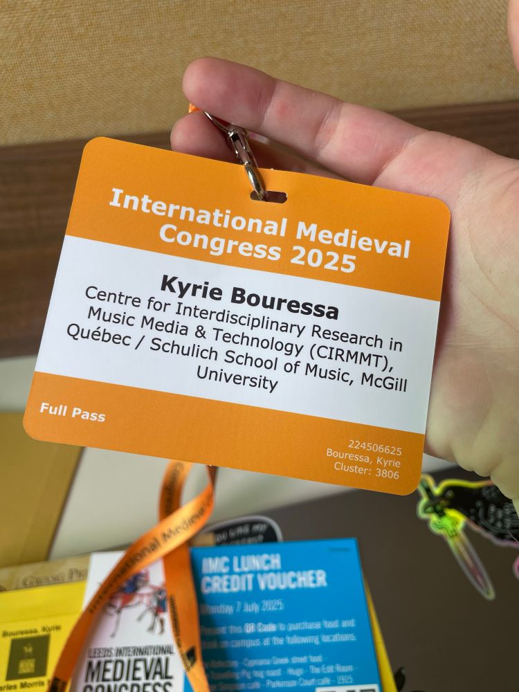 An orange conference tag for the International Medieval Congress 2025, identifying the poster—Kyrie Bouressa— and her affiliations with McGill University and the Centre for Interdisciplinary Research in Music Media and Technology.