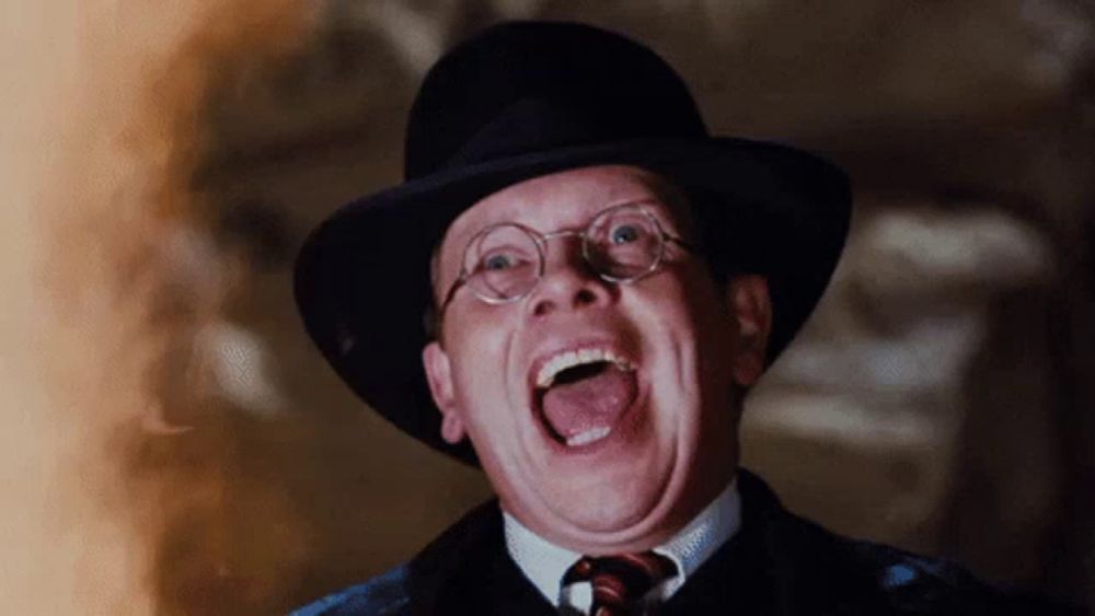 a man wearing glasses and a hat is laughing with his tongue out