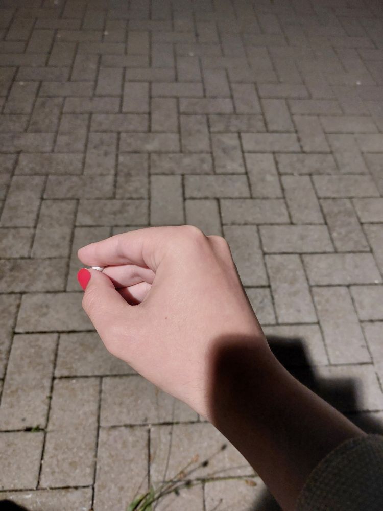 A picture of my hand holding a cigarette. My nails are painted with red nail polish