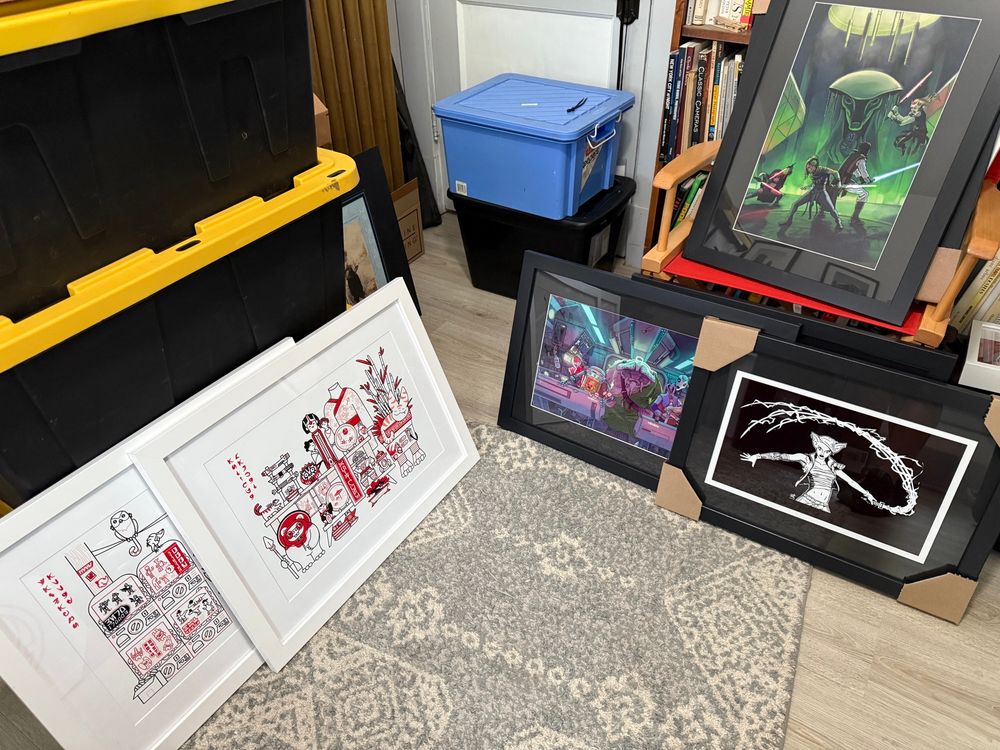 Framed art pieces by @hatfights.bsky.social (left two pieces in white, @jacobylow.bsky.social (bottom black frame on left, top black frame on right) and @magnatolvan (bottom right black frame).