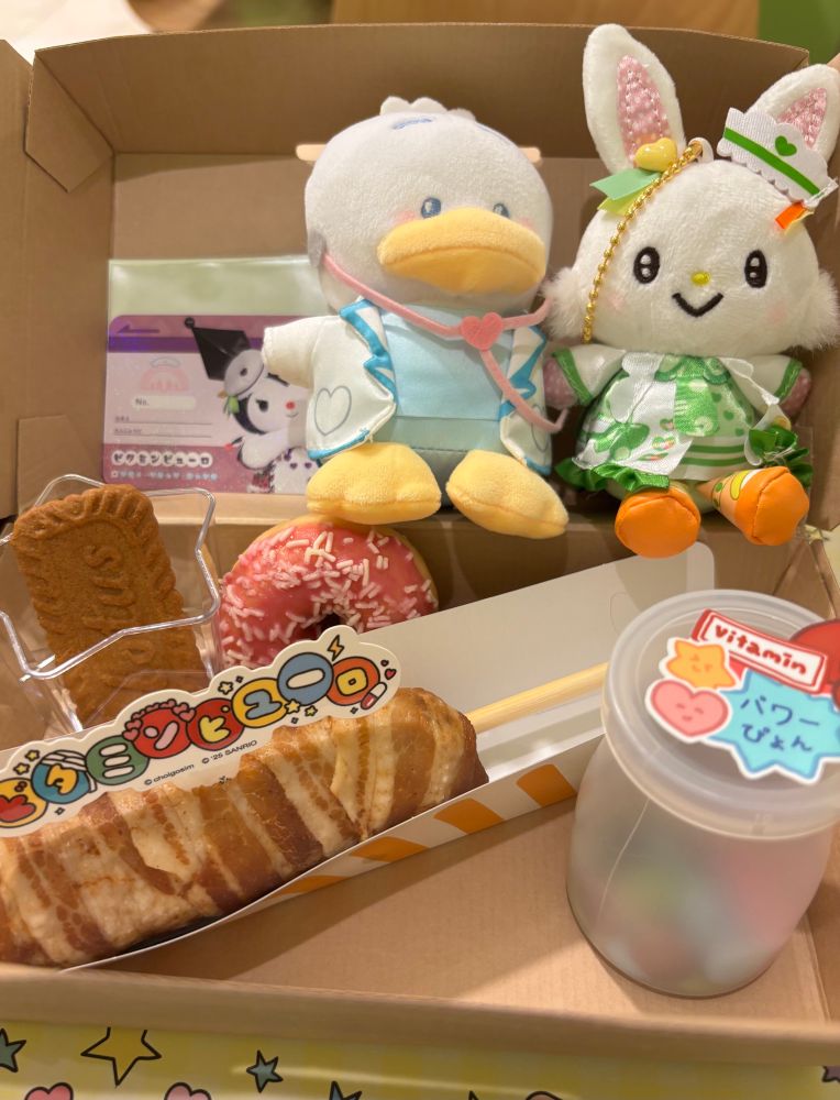 ビタミンピューロのモーニングボックス、肉巻きおにぎりとマーブルチョコ、ドーナツにビスケット。ペックルとメルのマスコット。クロミのノベルティカード