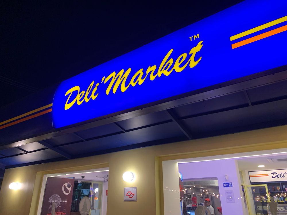 letreiro azul iluminado com o nome do estabelecimento “deli market”