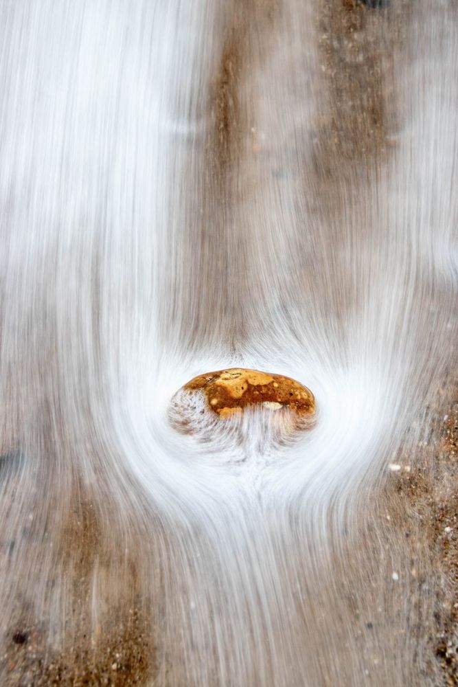 a pebble steadfastly refusing to be budged by the waves