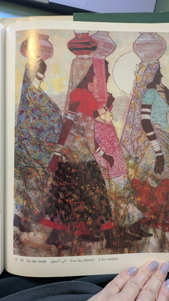 A full page of a painting called "to the fields." It shows four women walking while the sun sits in the lower half of the sky. They all have vases on their heads, and three of them are just balancing them without supporting them with hands. Their saris are vibrantly colored and patterned, each woman has a distinct outfit and their arms are adorned with silver bangles in different shapes. The one in the back has a whole veil covering her body and it's an explosion of color, it looks like a canopy of flowers against a blue sky. The woman in the foreground is all contrast, a solid red chola, an earthen sari with a pattern of white x's, and a red trimmed black skirt with splashes of red and orange. The lady behind her is a reverse of the foreground lady, a red sari with earthen skirt and scarfs. The rightmost woman has a light blue chola, a sari bunched at her head in a contrast of purple flowers and yellow splashes. She wears a red skirt with splashes of yellow and lilac.