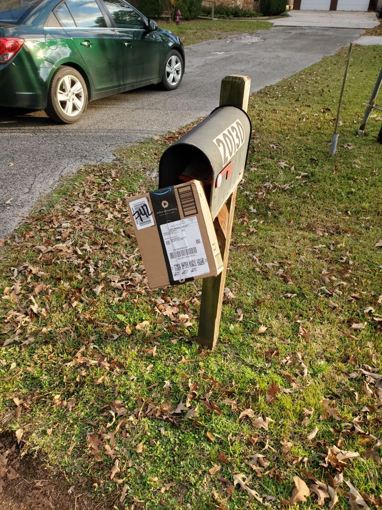 Package perched on the open door of the mailbox. 