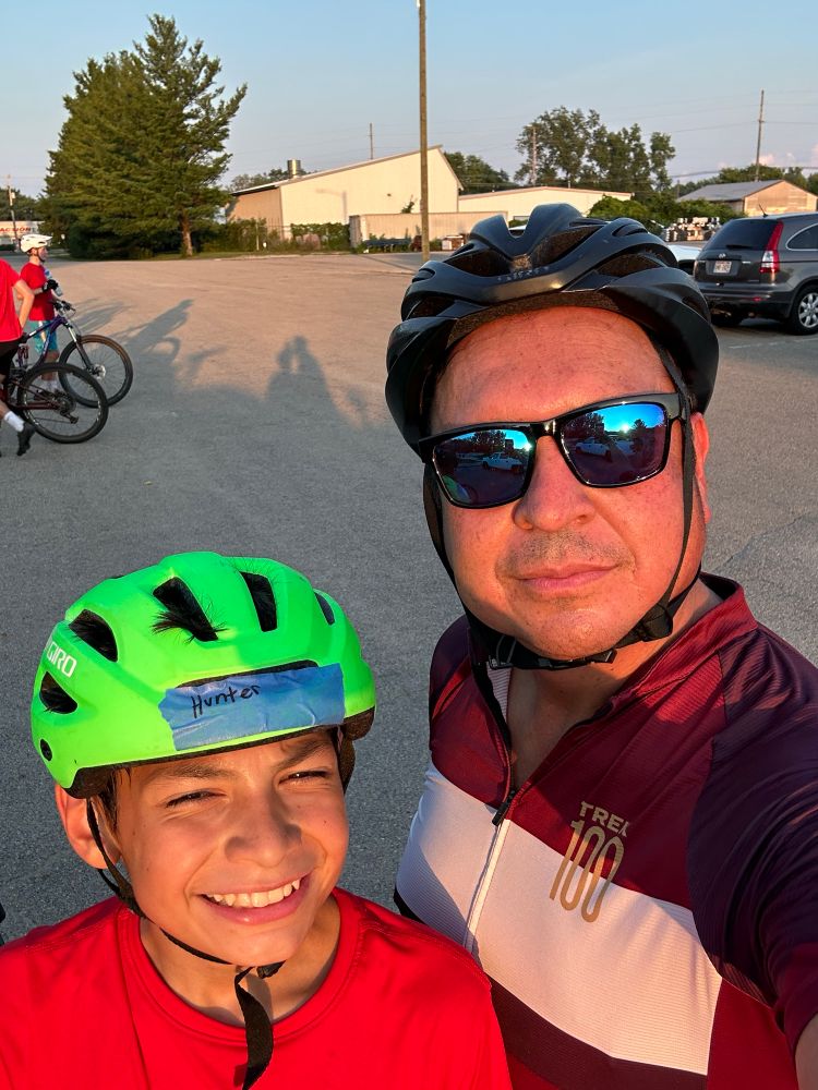 Man and son wearing bike helmets posing for picture