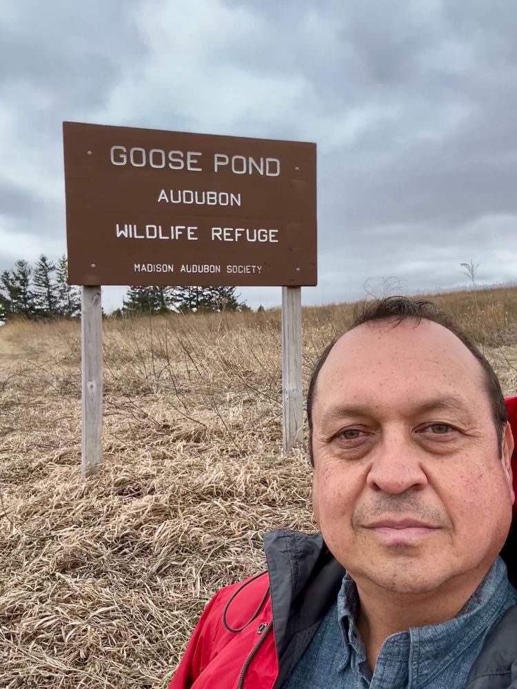 Man standing in front of wildlife refuge sign