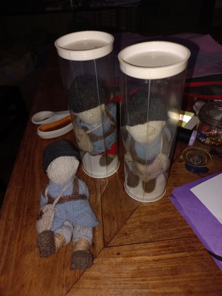 3 petits soldats tricotés 
2 ont des pantalons gris  et un a un pantalon rouge. Tous ont une gibecière grise  un casque noir un ceinturon et des bandes molletières marron. Ils n'ont pas de visage. 
