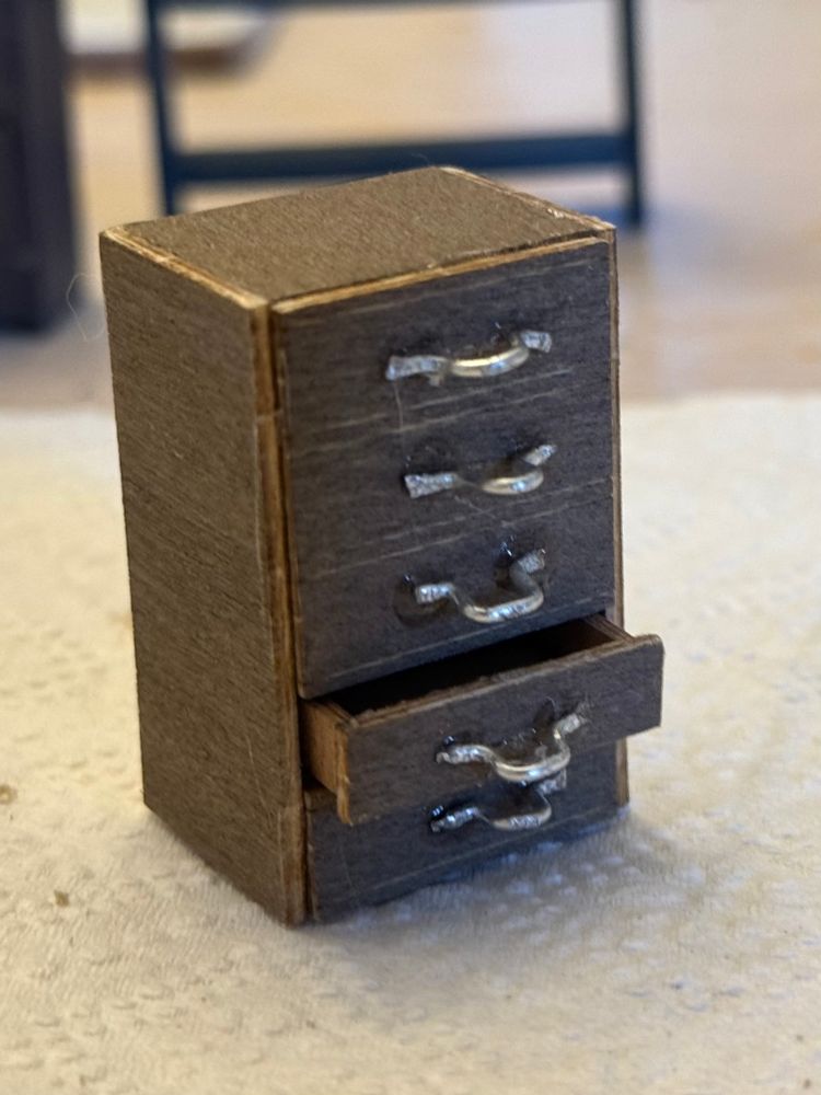 a medium brown cabinet with little metal handles that i twisted into a flat kind of omega shape and glued to the front of the drawers. one of the drawers(fourth from top) is actually open a little. also glue strands because im not excellent with the glue