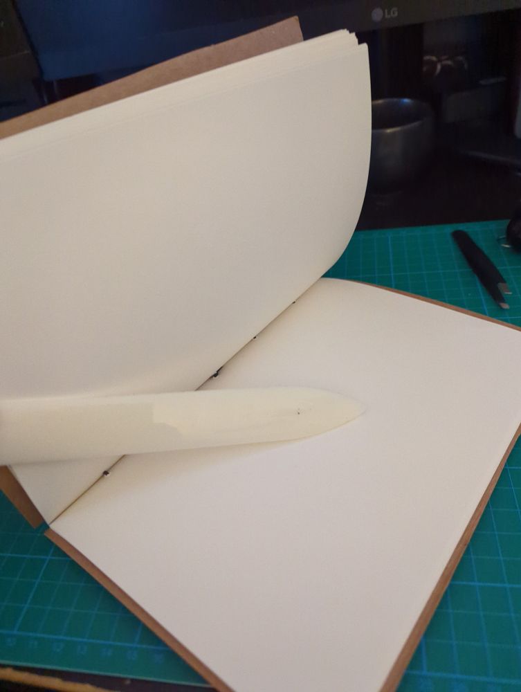 The same notebook, but splayed open by a bone folder to reveal unlined white pages.