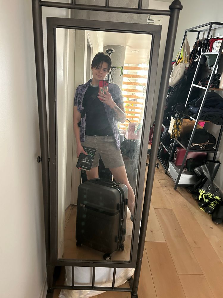 Micki still at home with a suitcase and a book 