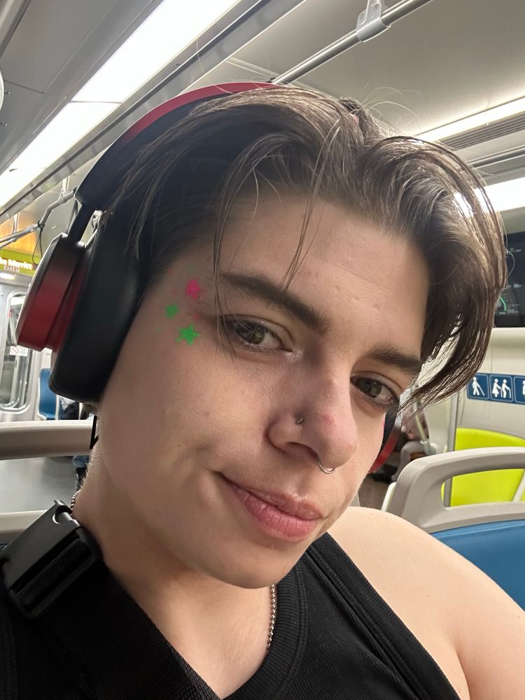 Micki’s face with neon green and pink stars by their right eye 