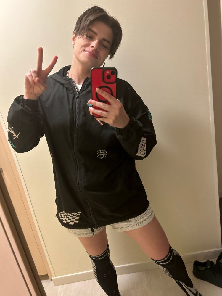 Micki wearing a very large windbreaker over knee high socks and shorts
