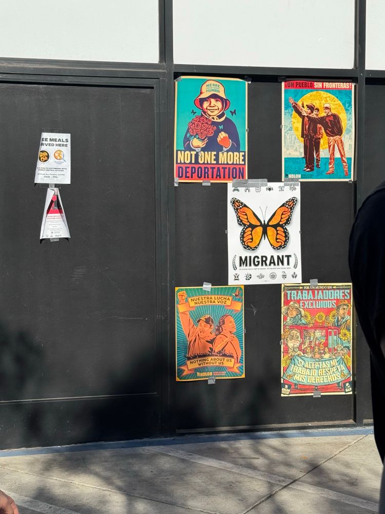 Posters in support of migrant workers and their rights posted against a black wall