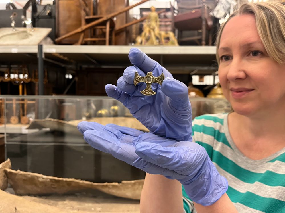 Kat Baxter, Leeds Museums and Galleries’ curator of archaeology, holding up a small gold Saxon cross. The top arm of the cross is missing.