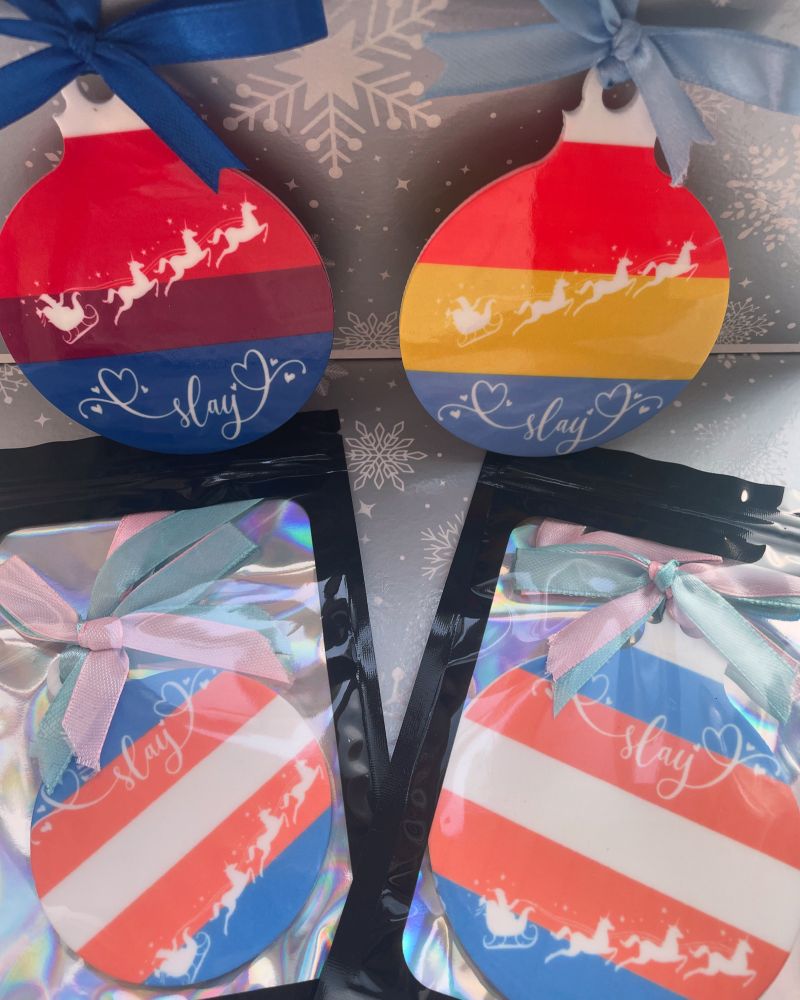 Bisexual, pansexual and trans flags on Christmas decorations that read slay and Santa in his sleigh being pulled by unicorns. 
All LGBTQ flags available. 