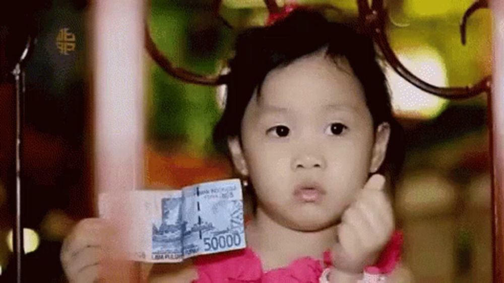 a little girl in a pink dress is holding a money bill that says 50000 .