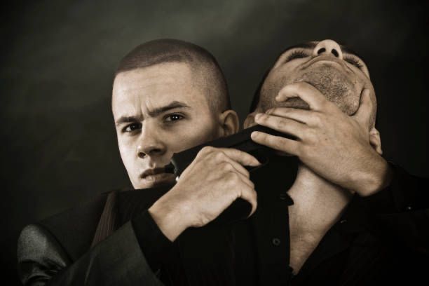 An ugly, deranged man, possibly a child sex predator or Wall Street analyst, holds a pistol to the neck of another man.