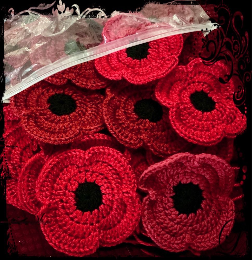 A plastic bag with red crocheted poppies spilling out of it.